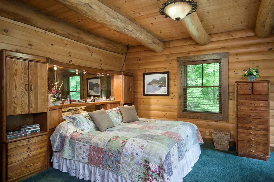 bedroom with a window, king-sized bed with floral bed sheets, brown wooden cabinets