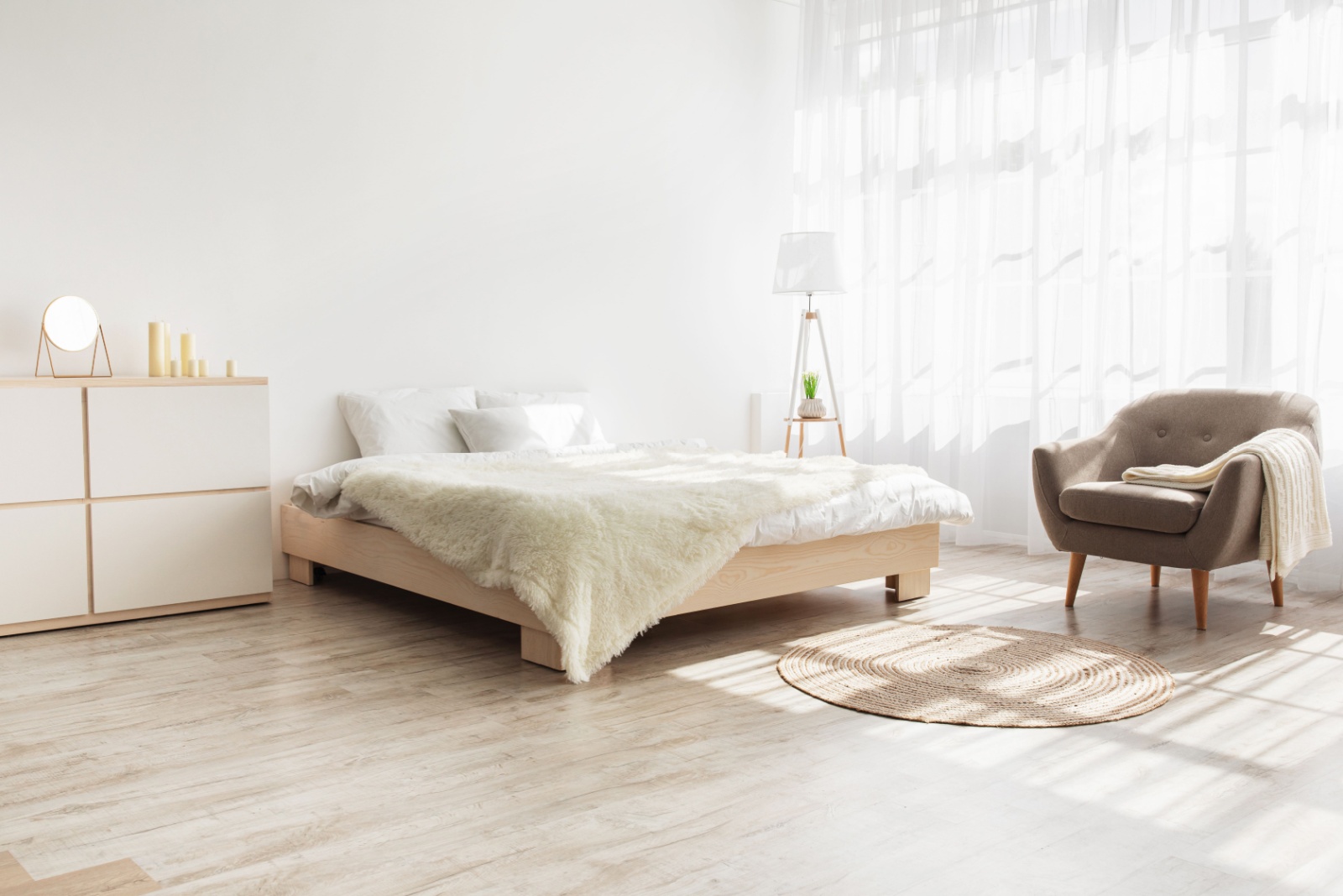 bedroom with a bed, a beige chair in the corner of the room, a white and light beige cabinet, white curtains and a tall white lamp