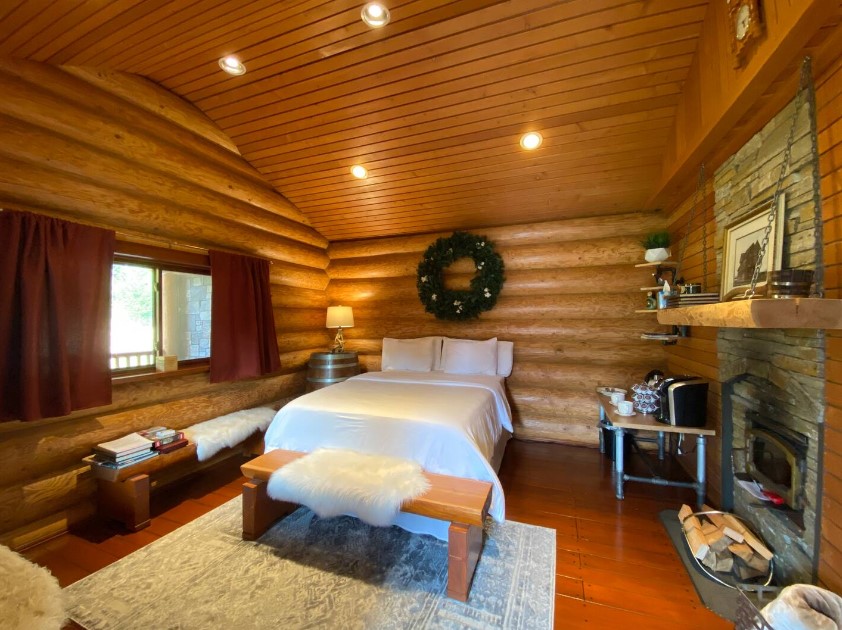 bedroom with a bed and wooden walls, fireplace and a shelf above it