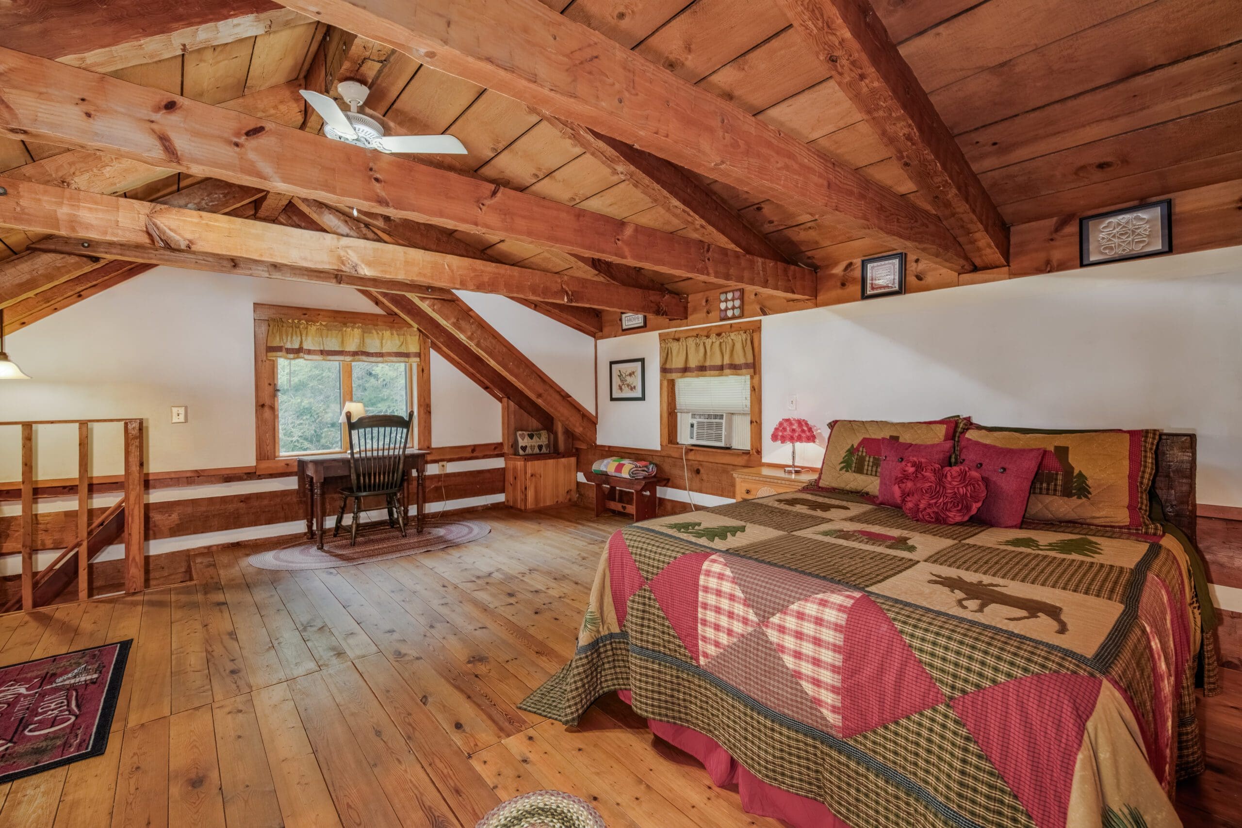 bedroom with a queen-sized bed, a lot of space, brown desk under the window and a brown rustic chair