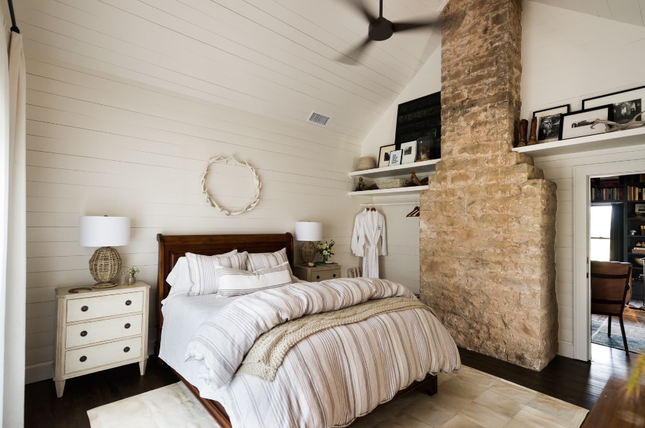 bedroom with a wooden white wall, white bedside table, brown bed frame of a comfy bed