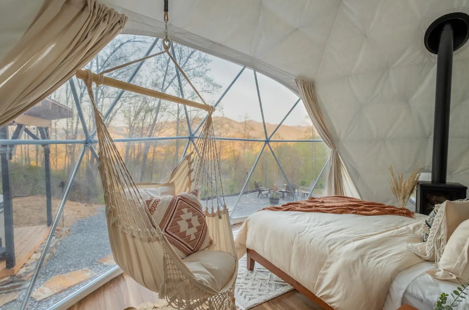 bedroom with floor to ceiling windows, hanging chair, comfy bed