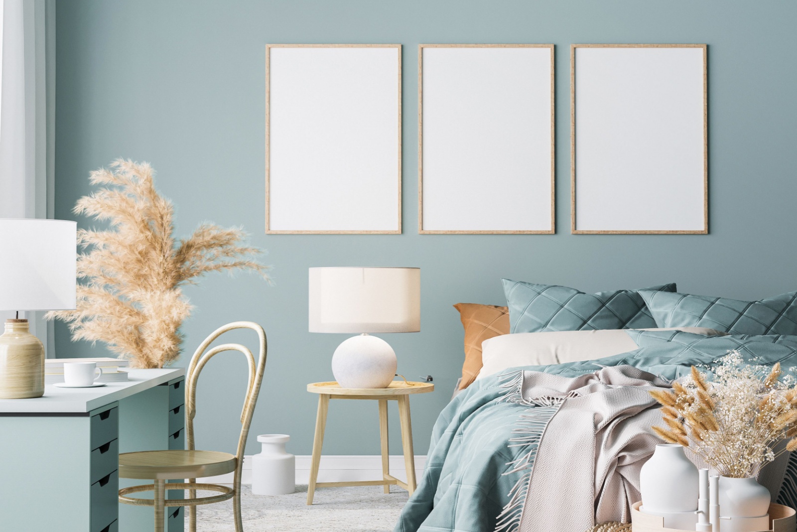 bedroom with light blue walls, a bed with light blue bedsheets, light blue desk accompanied by a brown chair, light brown bedside table and three artworks above the bed