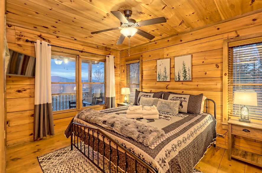 bedroom with a king-sized bed, two framed photos above, windows on two walls, bedside tables with lamps