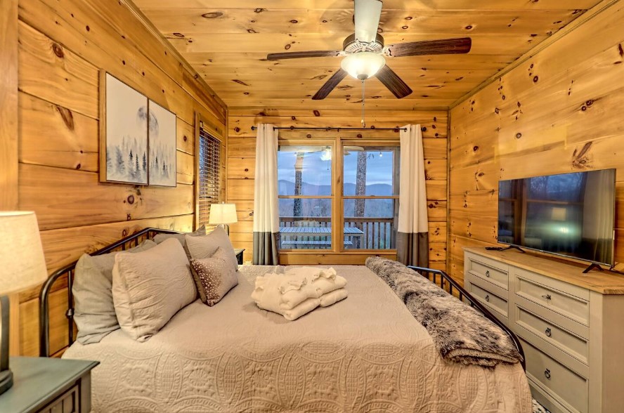 bedroom with a queen-sized bed and white bedsheets, flat screen tv and windows