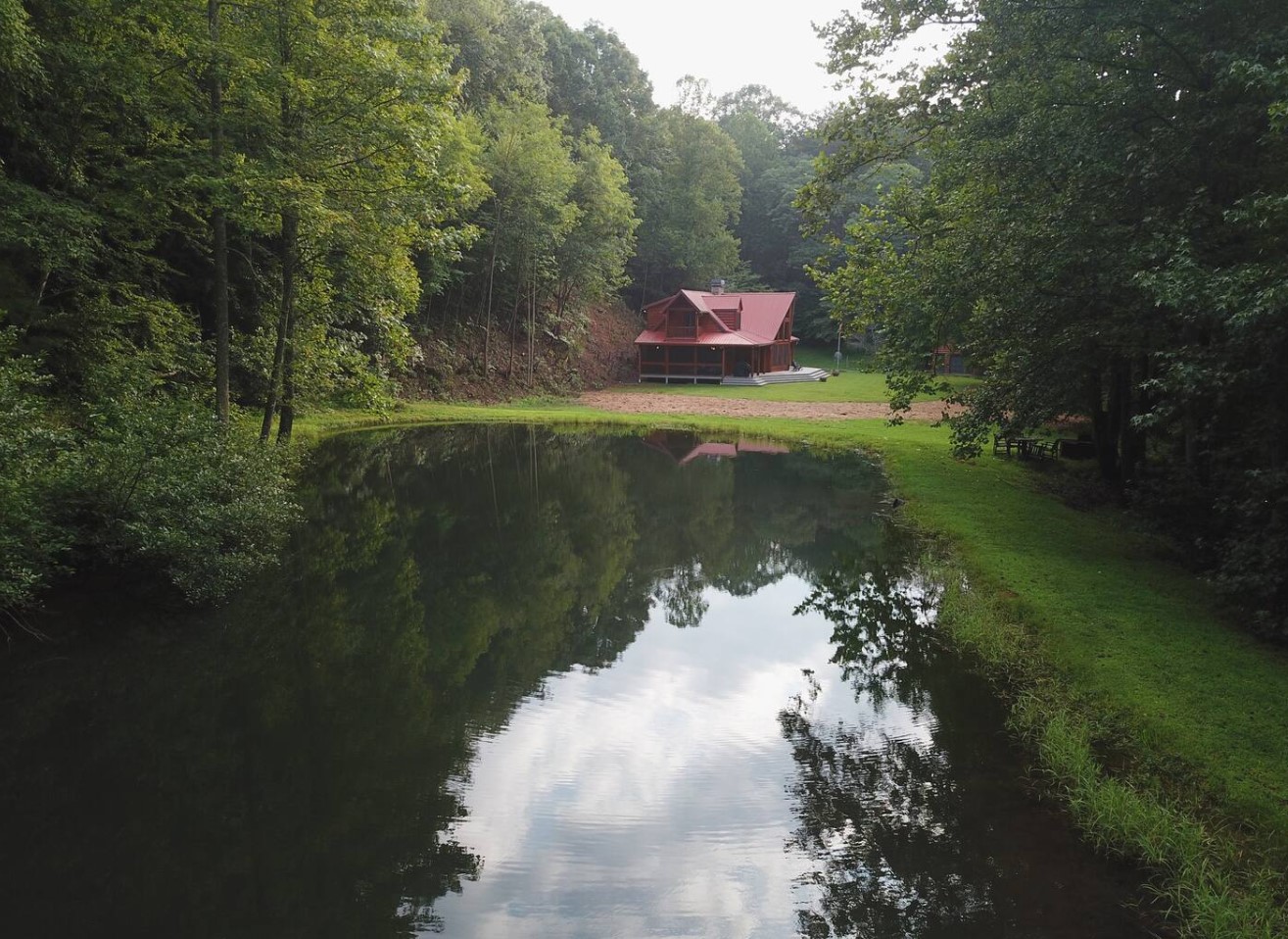 Cabin next to a pond with a red roof