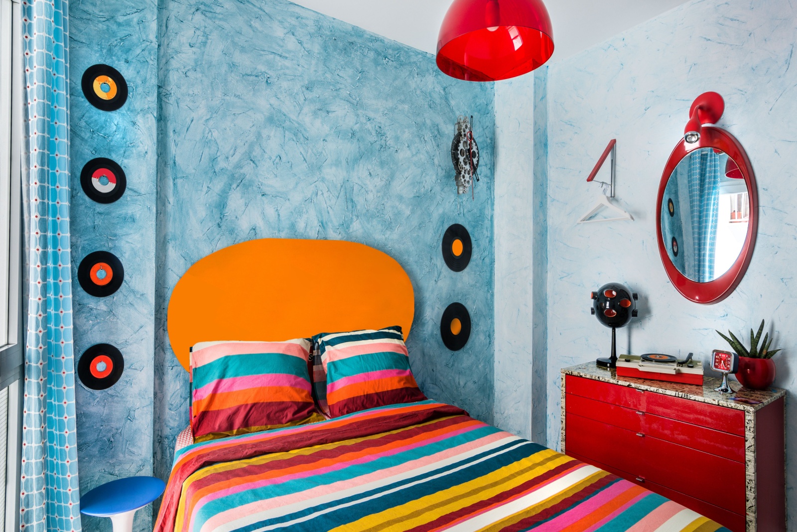 colorful 60s bedroom with colorful decor, blue walls, red cabinet, vinyls on the wall