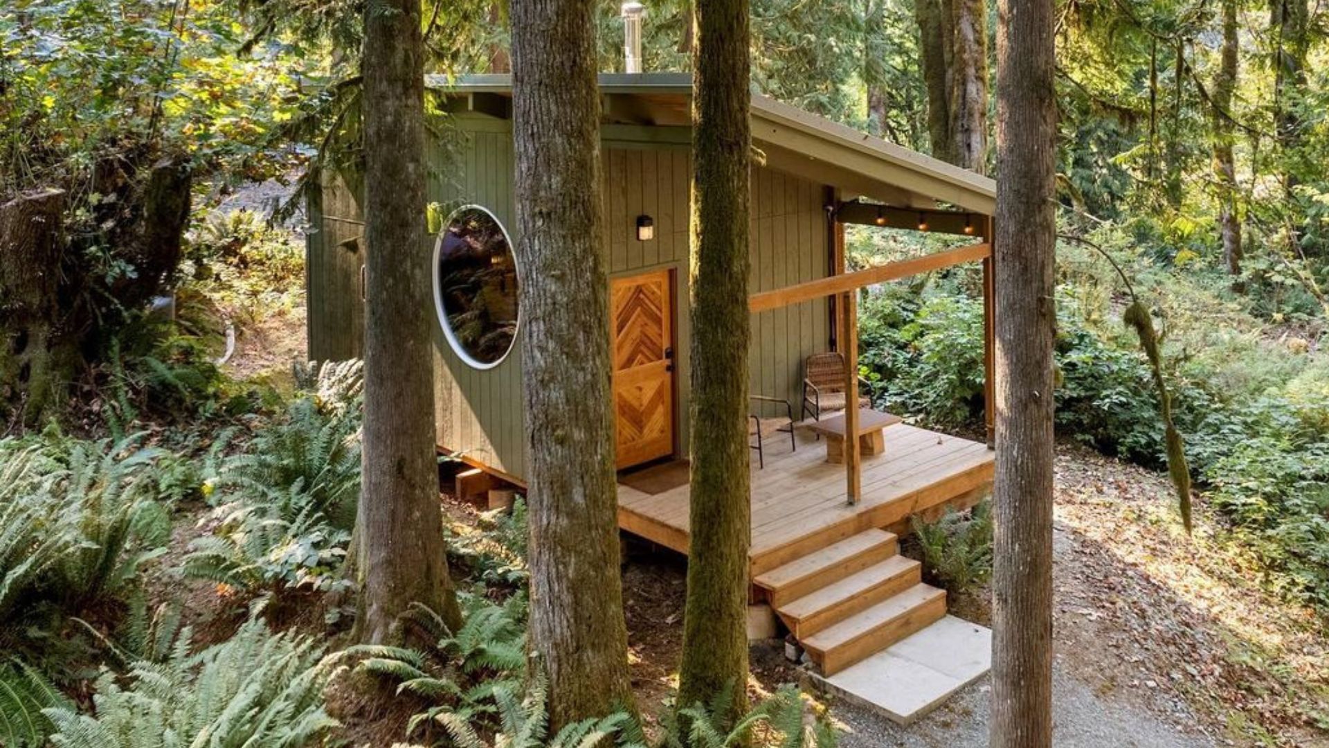 exterior of the cyclops cabin with a small porch, a round window on the side, surrounded by trees