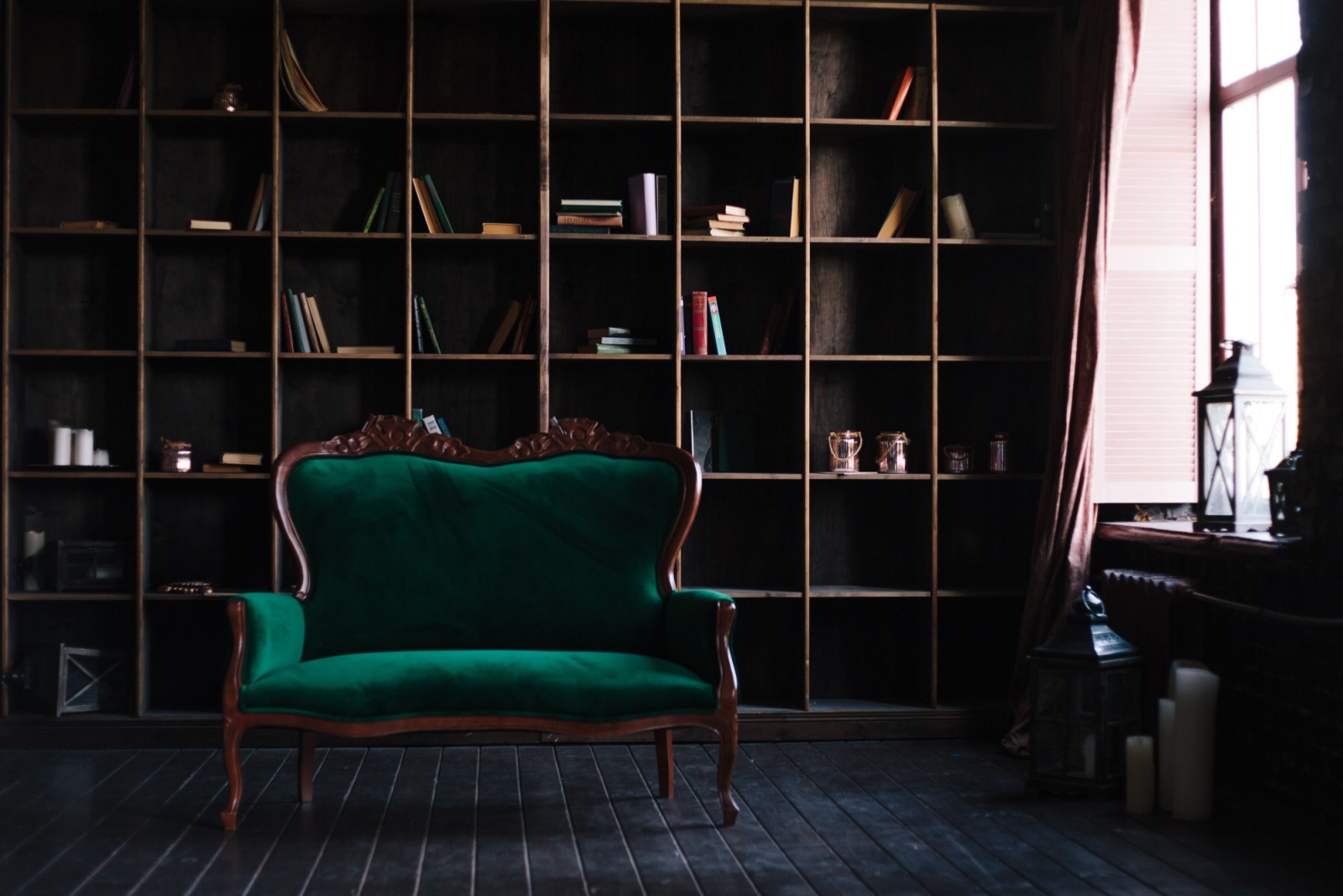 dark wooden shelf with books and decor, dark green couch with a wooden frame