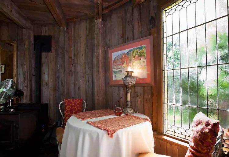 dining area with a round table accompanied by two chairs, wooden walls and a frozen glass