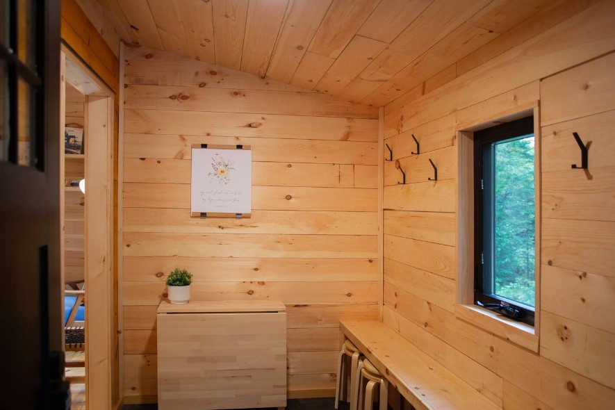 entryway hallways with wooden walls, brown folded cabinet and a bench with stools under it