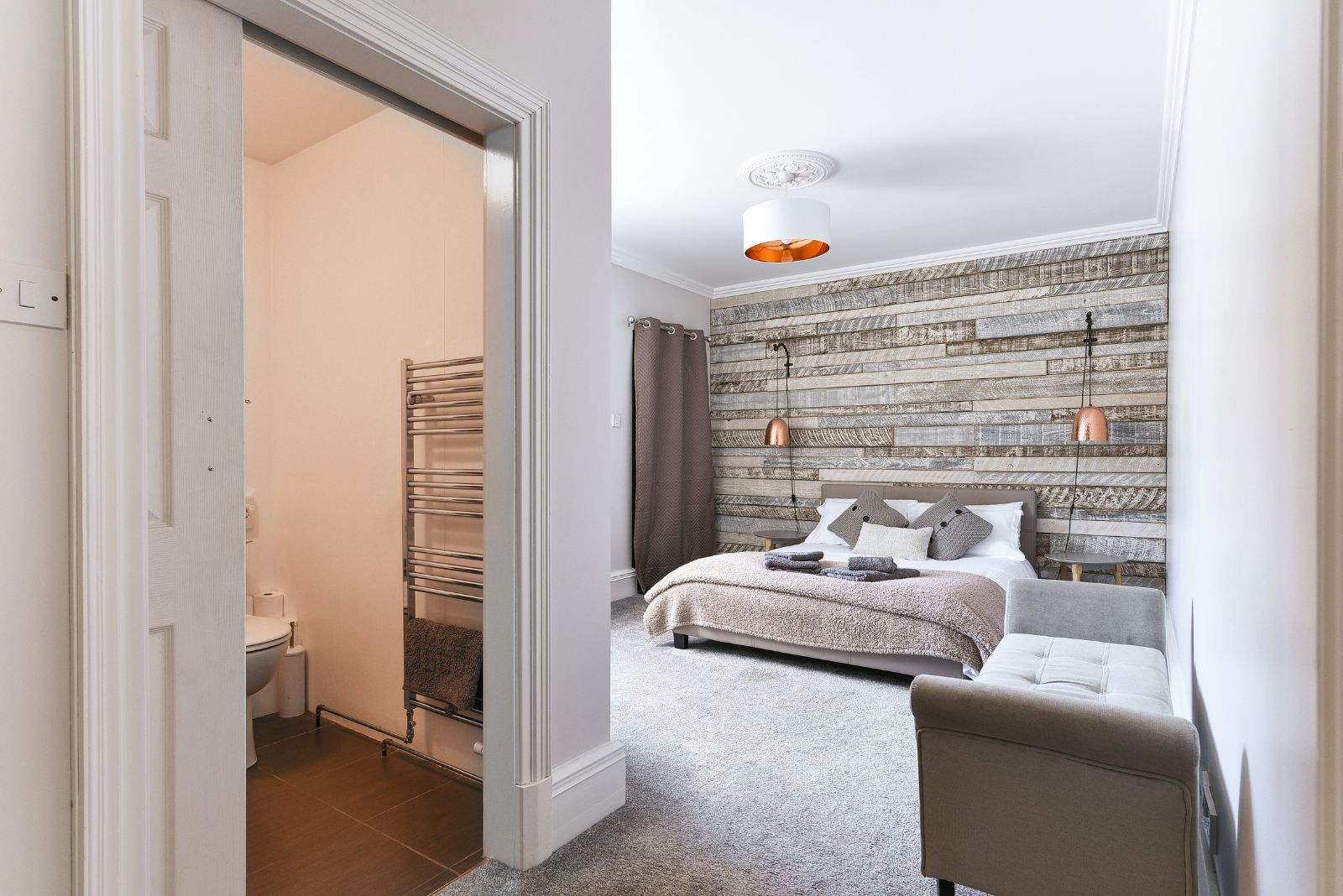 bright bedroom with rustic grey wood planks on the wall behind the bed