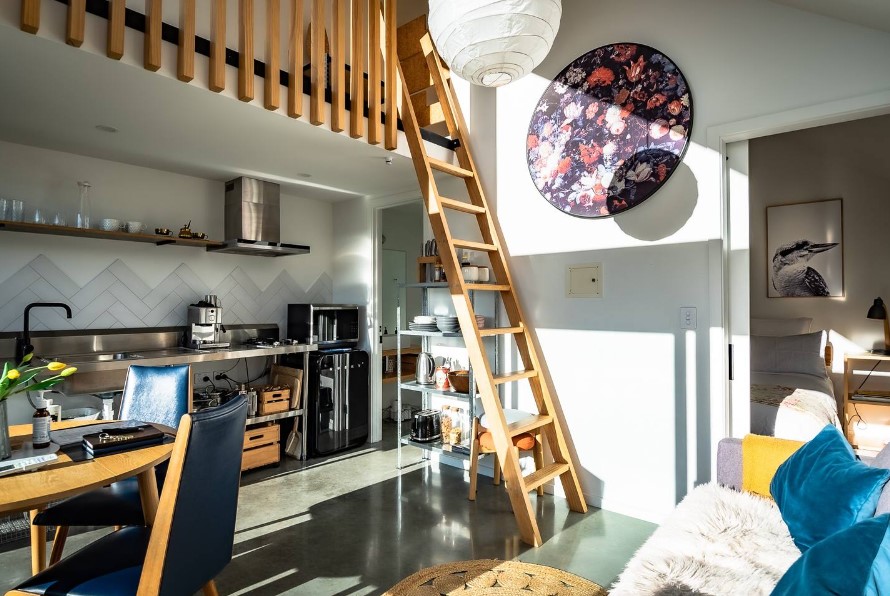 interior of a tiny home with ladders and a kitchen in the background, a lot of sunlight