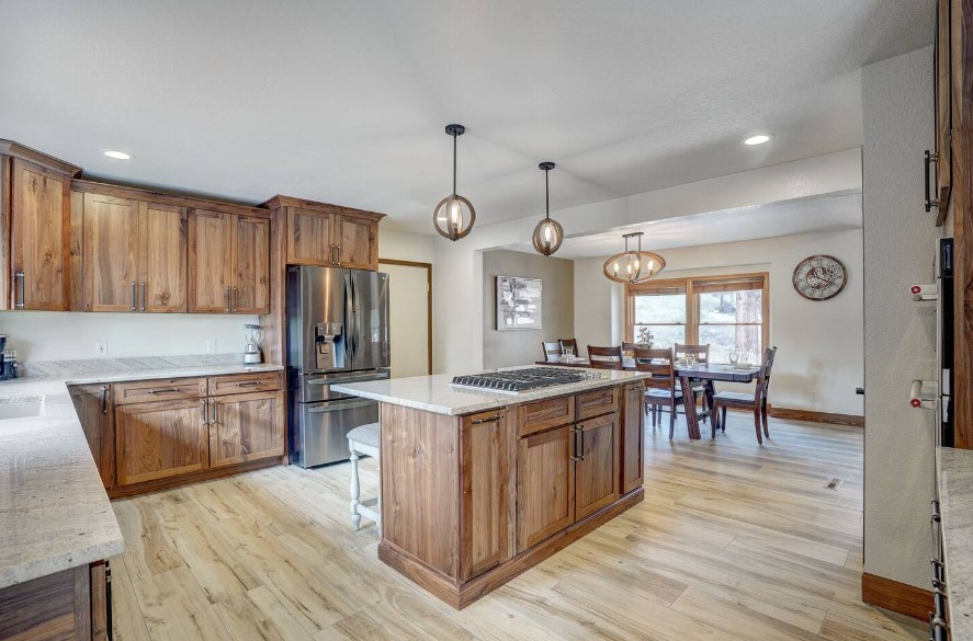 kitchen with brown cabinets and white marble l-shaped countertop and island