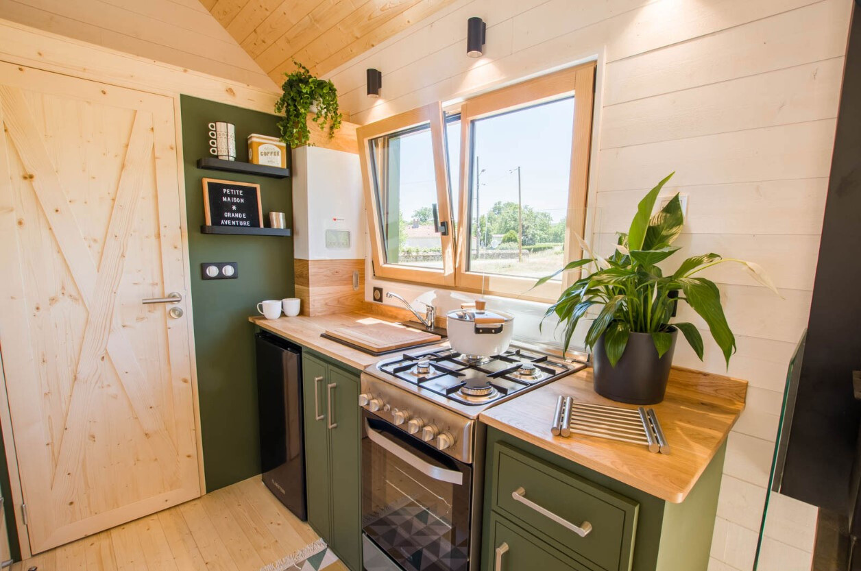 kitchen with dark green cabinets and a wooden countertop and a window above the cabinet