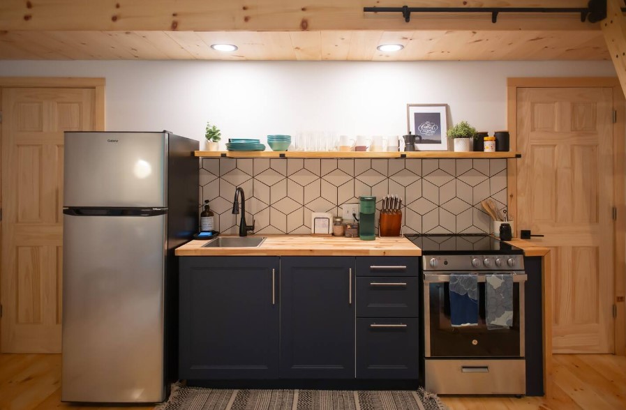 kitchen with black cabinets, brown wooden countertops, a wooden shelf