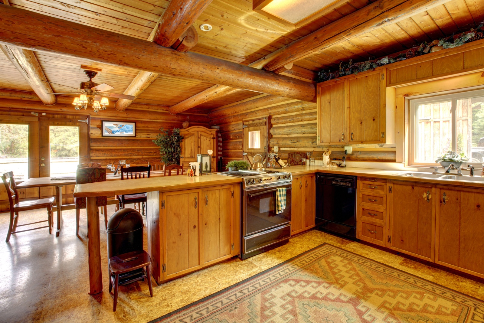 kitchen of a log cabin with brown wooden cabinets and l-shaped countertop and wooden walls