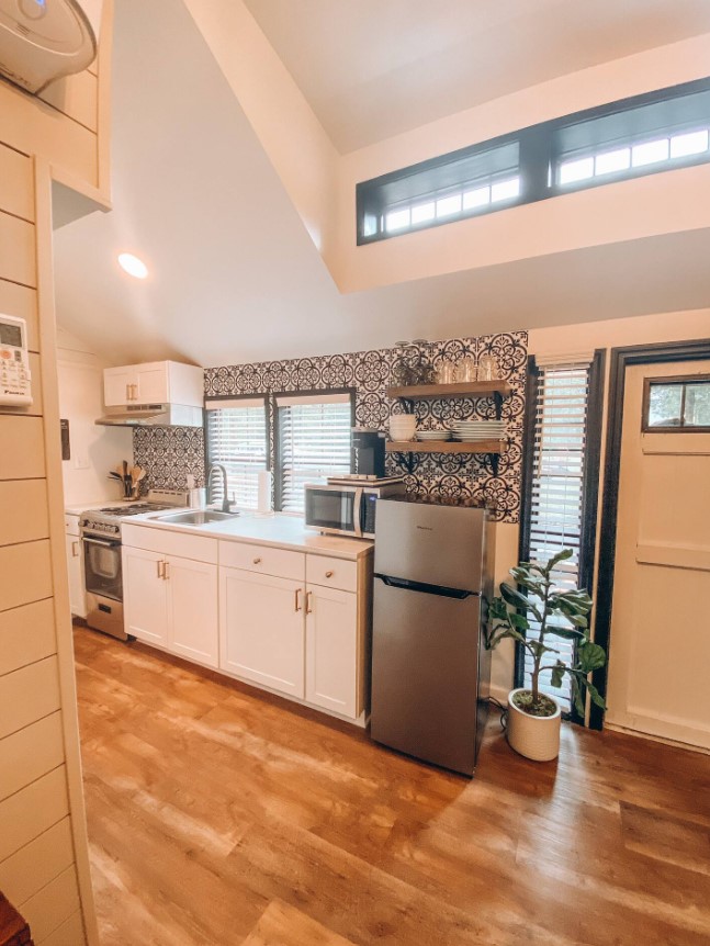 kitchen with one black and white textured wall, white cabinets, wooden floors