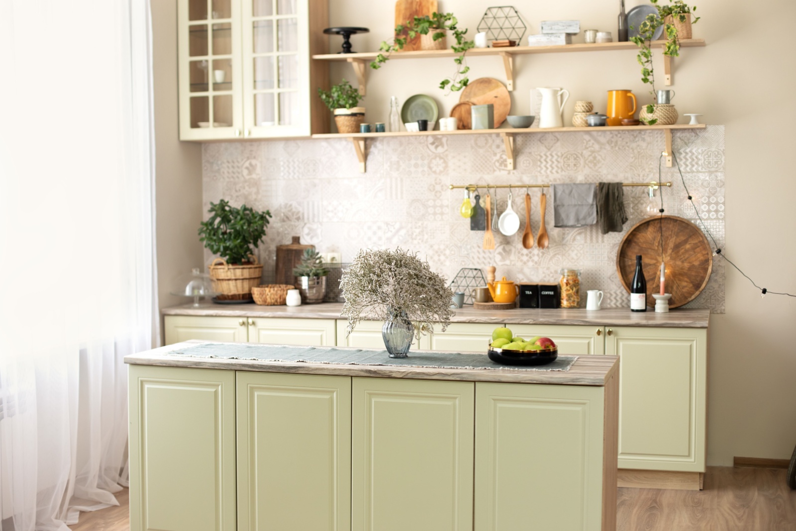 kitchen with light green cabinets, shelves filled with equipment