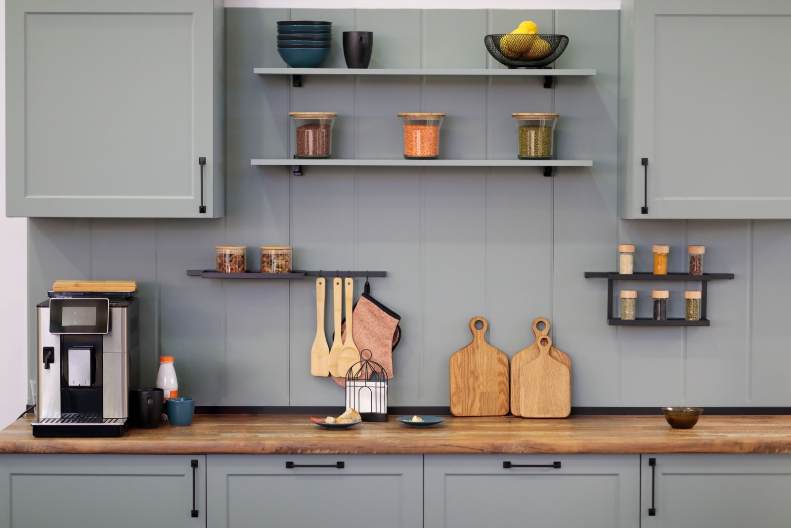 kitchen with gray blue cabinets, open shelves with amenities and brown, wooden countertop