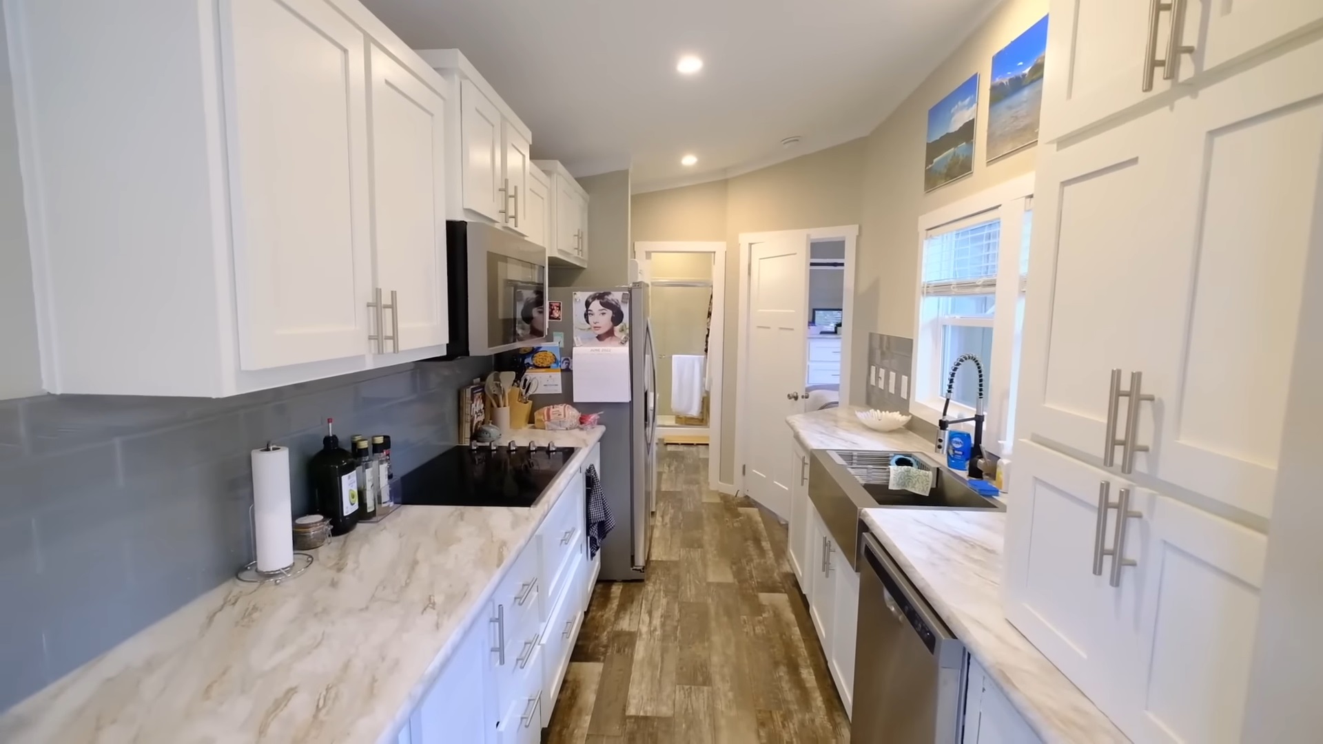 kitchen with white countertops on both sides of the room, white cabinets all around and big windows