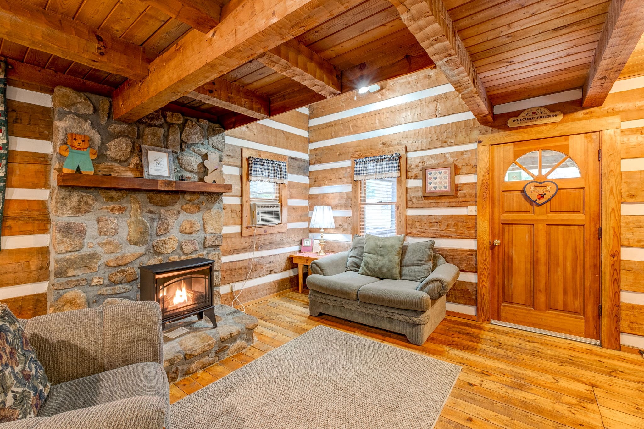 living area with two sofas, a fireplace, a shelf above the fireplace and wooden beams