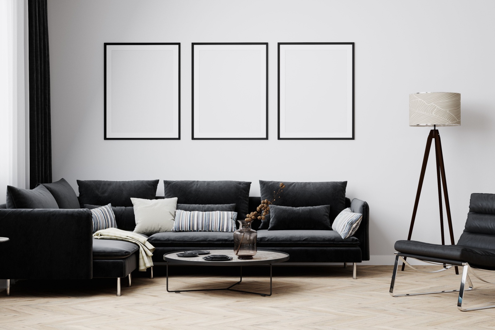 living room with a black couch, black chair, round table, white walls, three white hung art pieces, tall black and white lamp