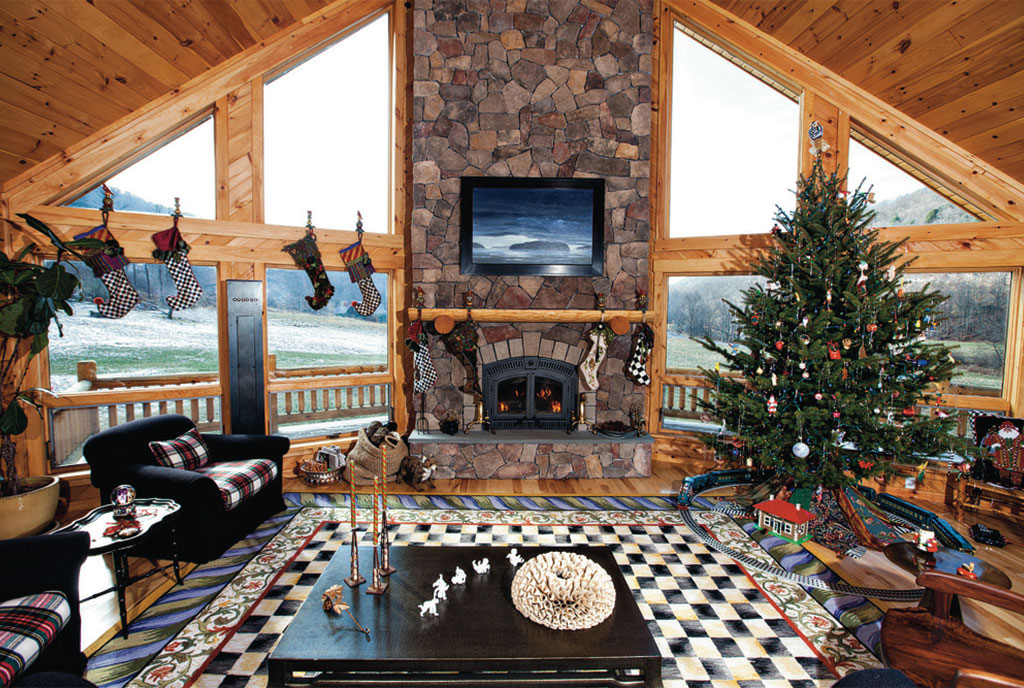 living room with a fireplace, flat screen tv, floor to ceiling windows, brown table, black sofas