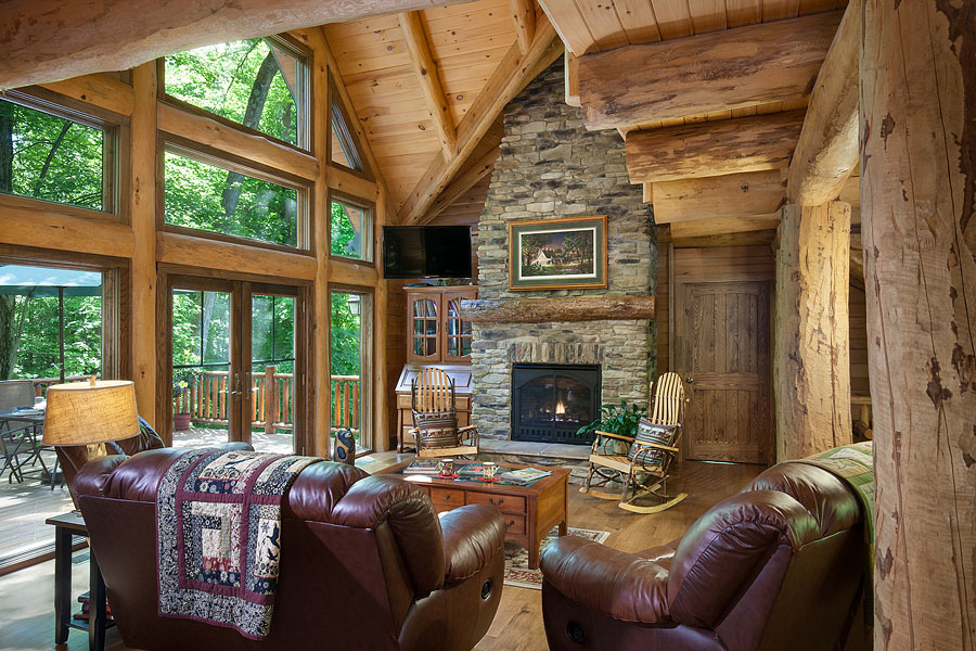 living room with brown, leather couches, rocking chairs, flat screen tv in the corner, fireplace, floor-to-ceiling window