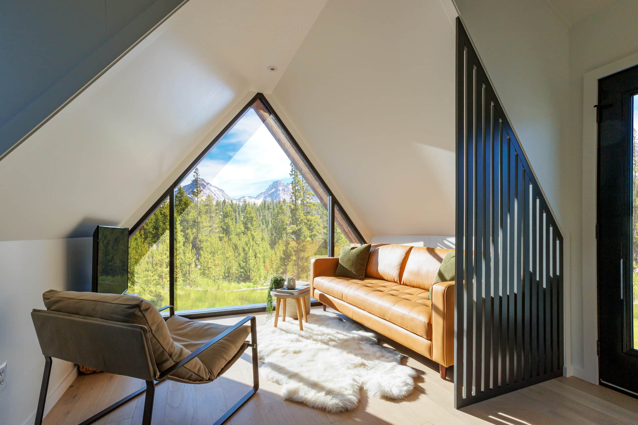 living room with a huge window, orange couch, soft white rug, tiny table, gorgeous views, flat screen tv and a chair