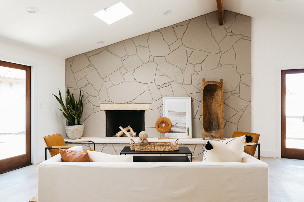 living room with a slanted beige wall with crack design, fireplace, light beige couch