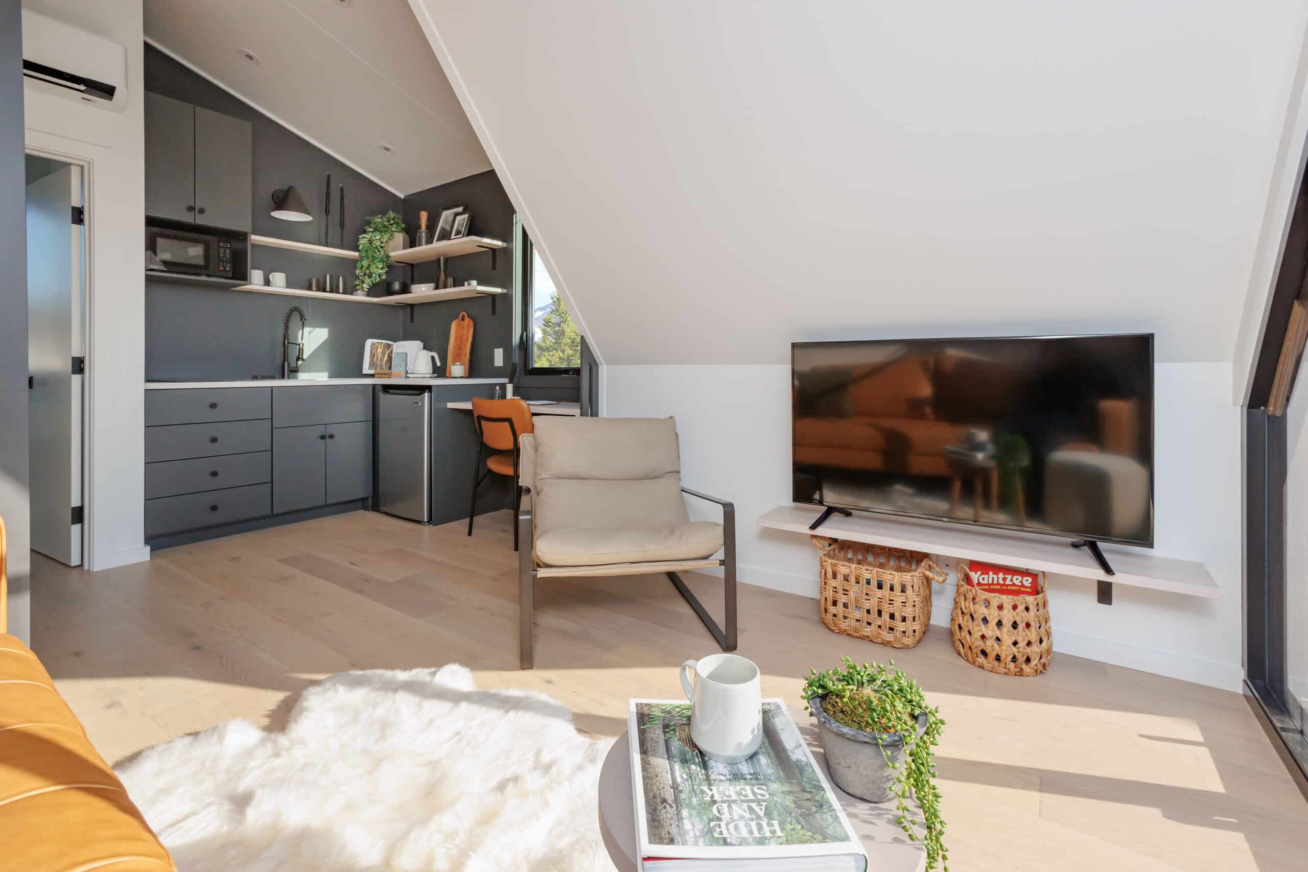 living room with a flat screen tv, chair, white rug, tiny round table