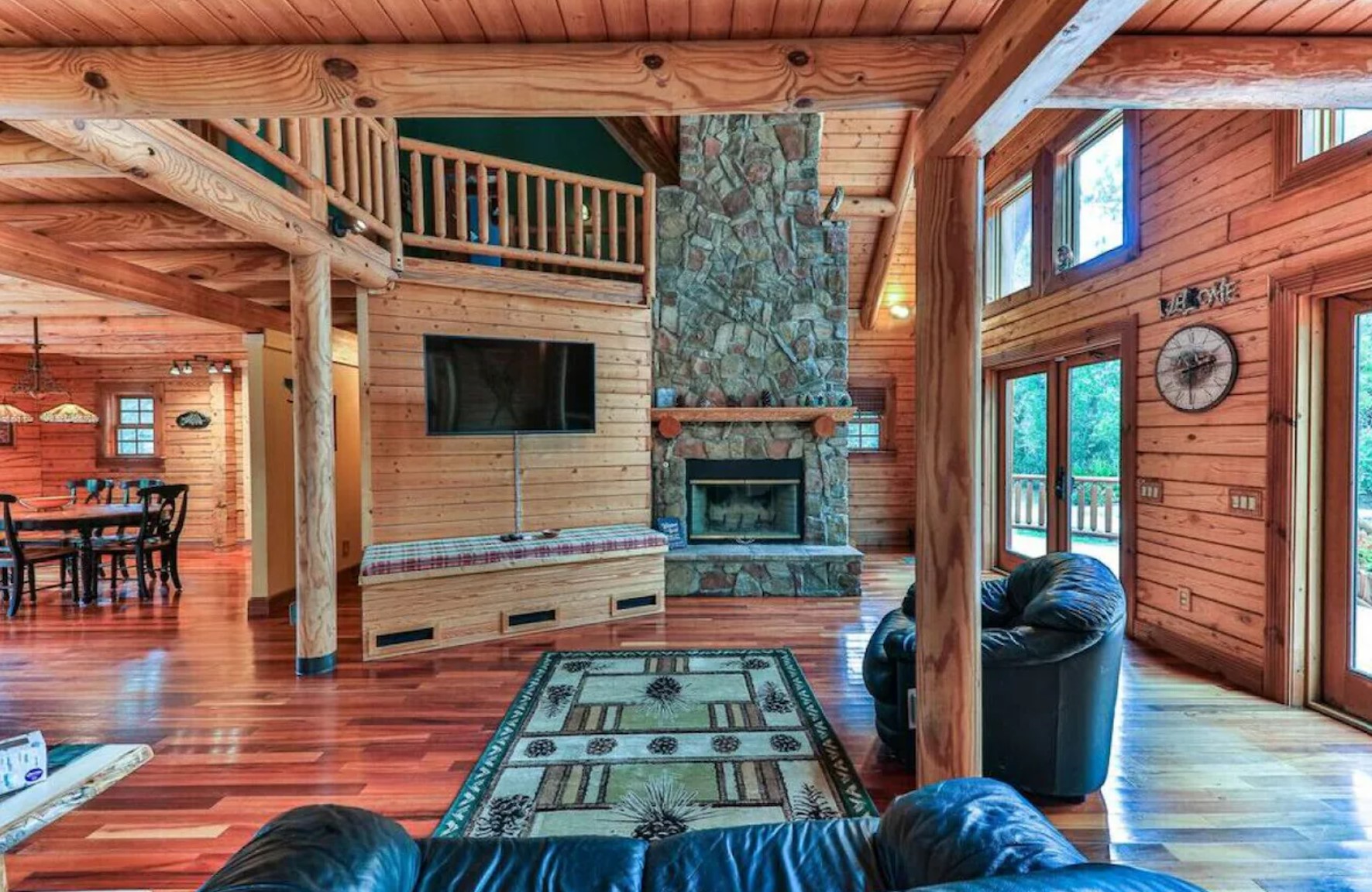 living room with a stone fireplace, black couch and a TV