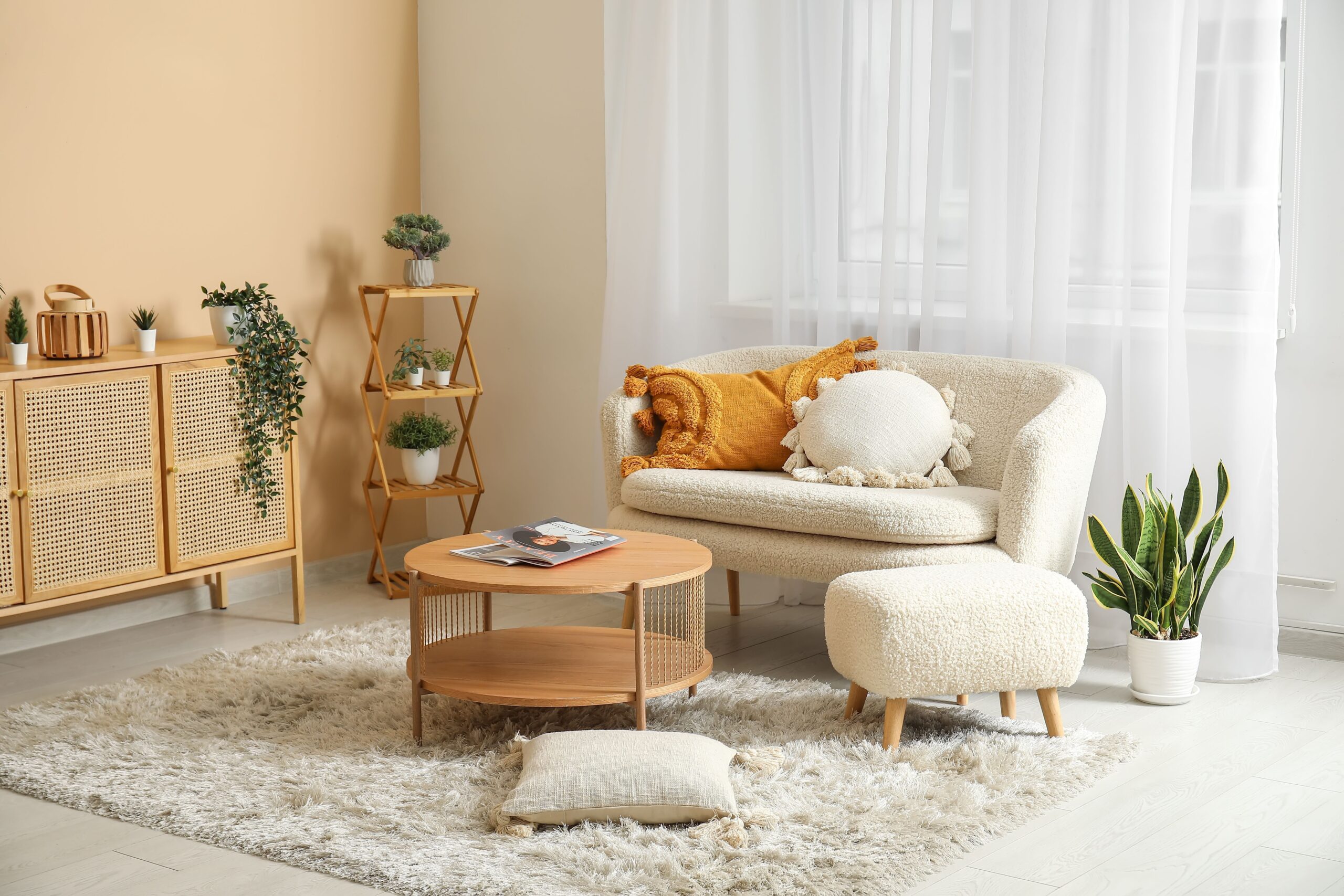 living room with a white comfy couch, white comfy chair, round brown table, brown cabinets, thin brown shelf