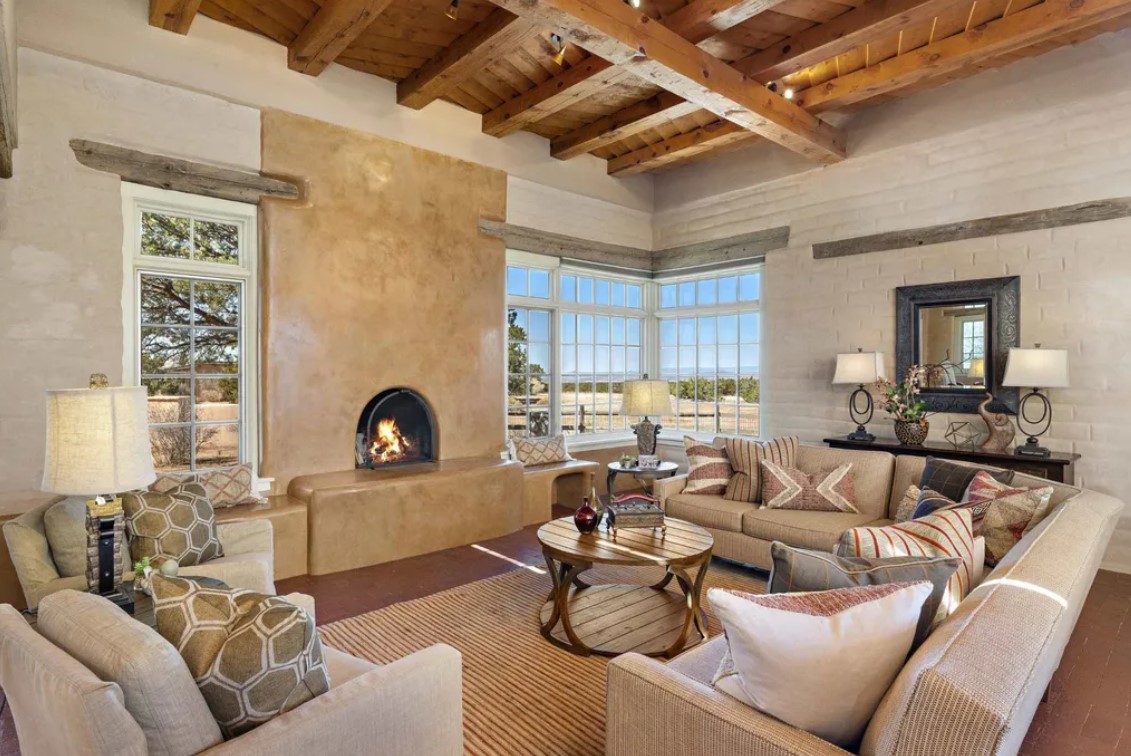 farmhouse living room with a beige couch, wooden ceiling with wooden beams, fireplace