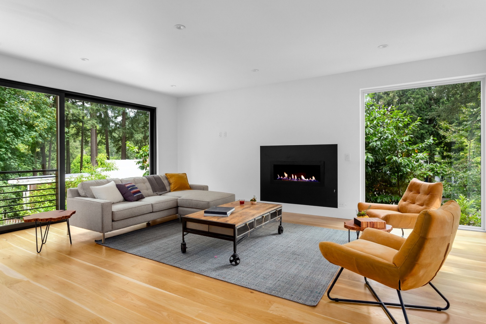 living room with floor-to-ceiling windows, gray carpet, orange chairs, gray couch, fireplace