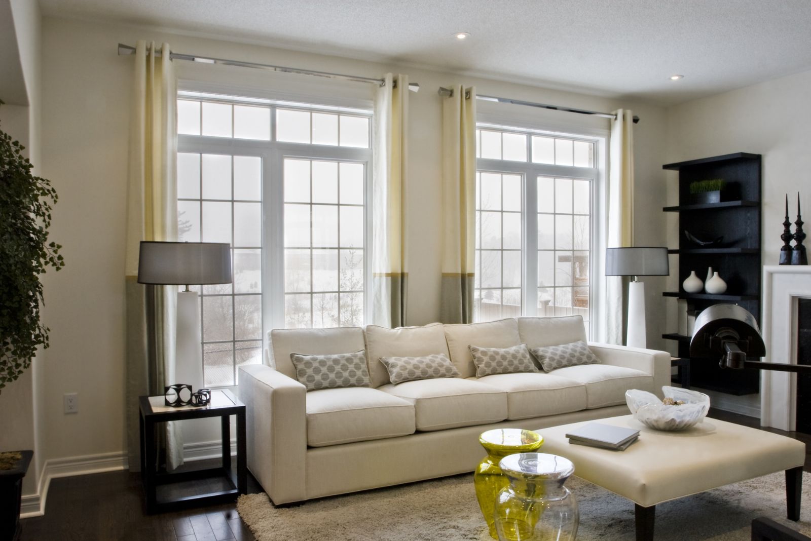 Living room with a white couch, huge windows and black decor