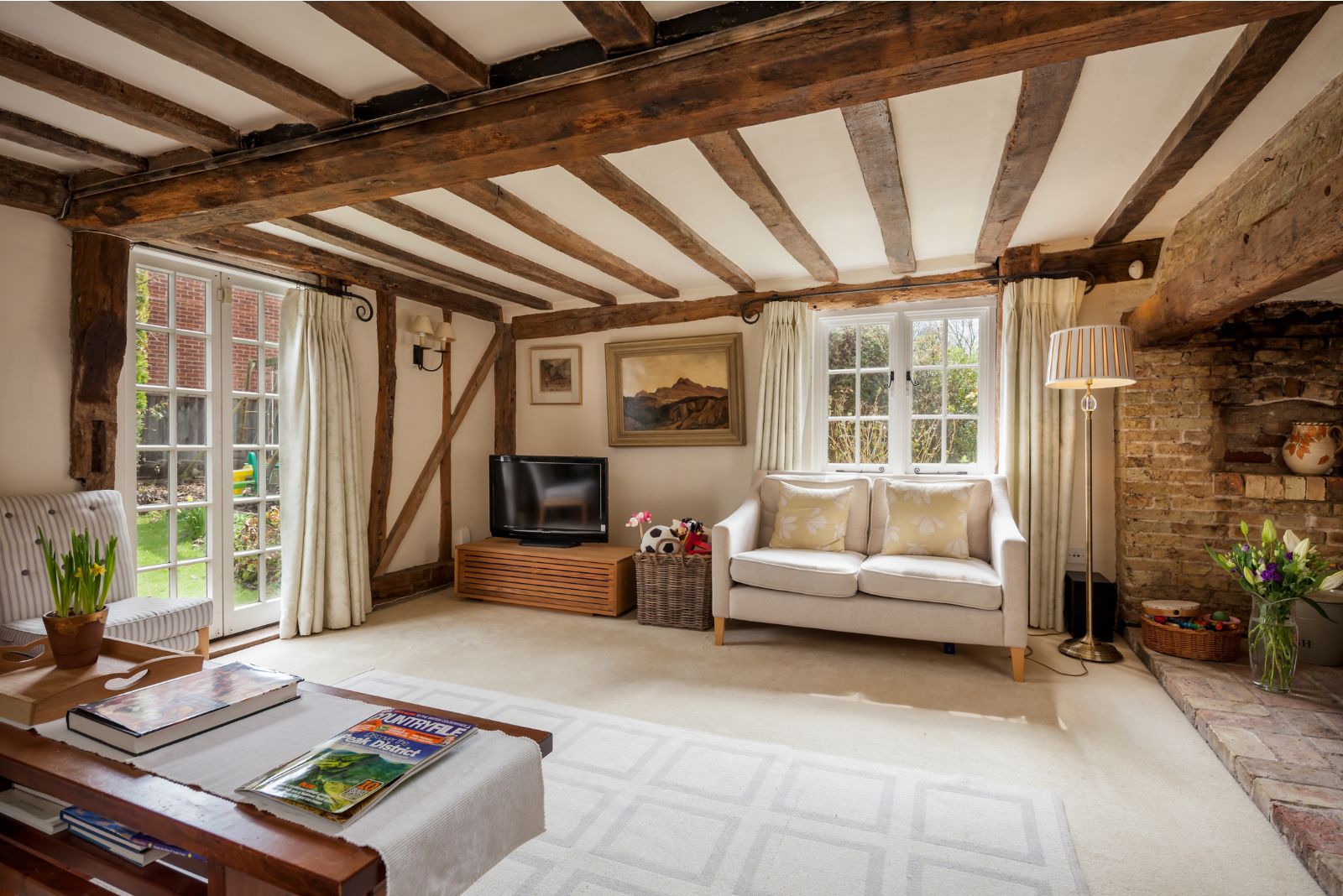 Living room with wooden beams on ceiling with a stone corner