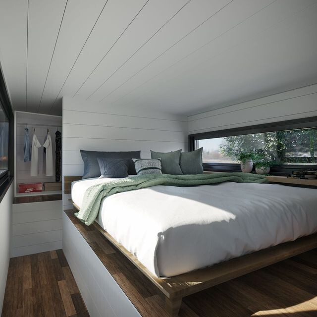 loft bedroom with white walls, queen-sized bed, window spread out right next to the bed, white closet