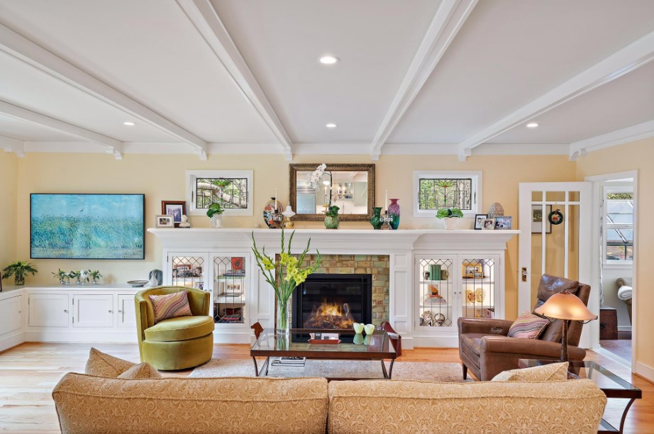 maximalist living room with a beige wall, beige couch, a lot of decor on the white cabinets