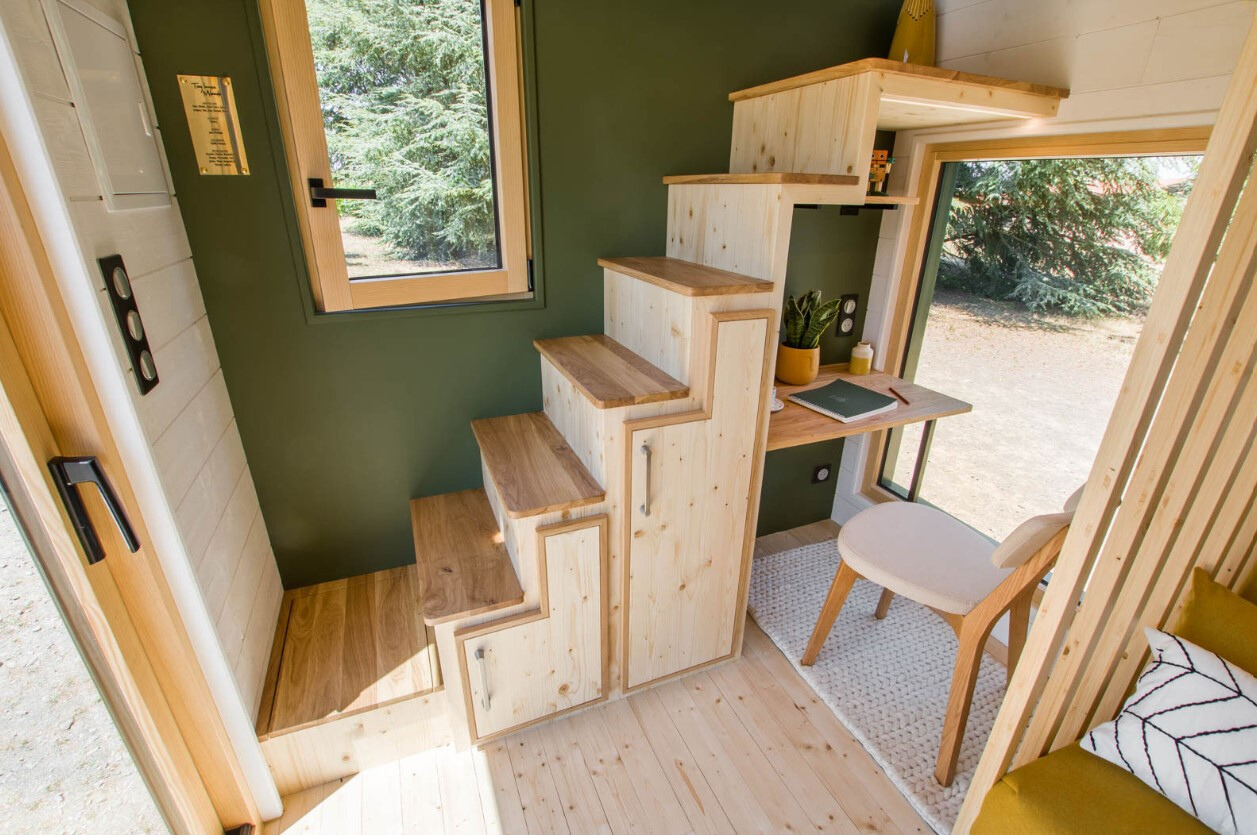 office area with a wooden desk and a chair under the wooden stairs