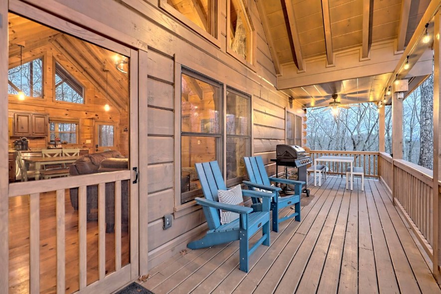 porch with blue chairs, black grill and a white dining table with benches