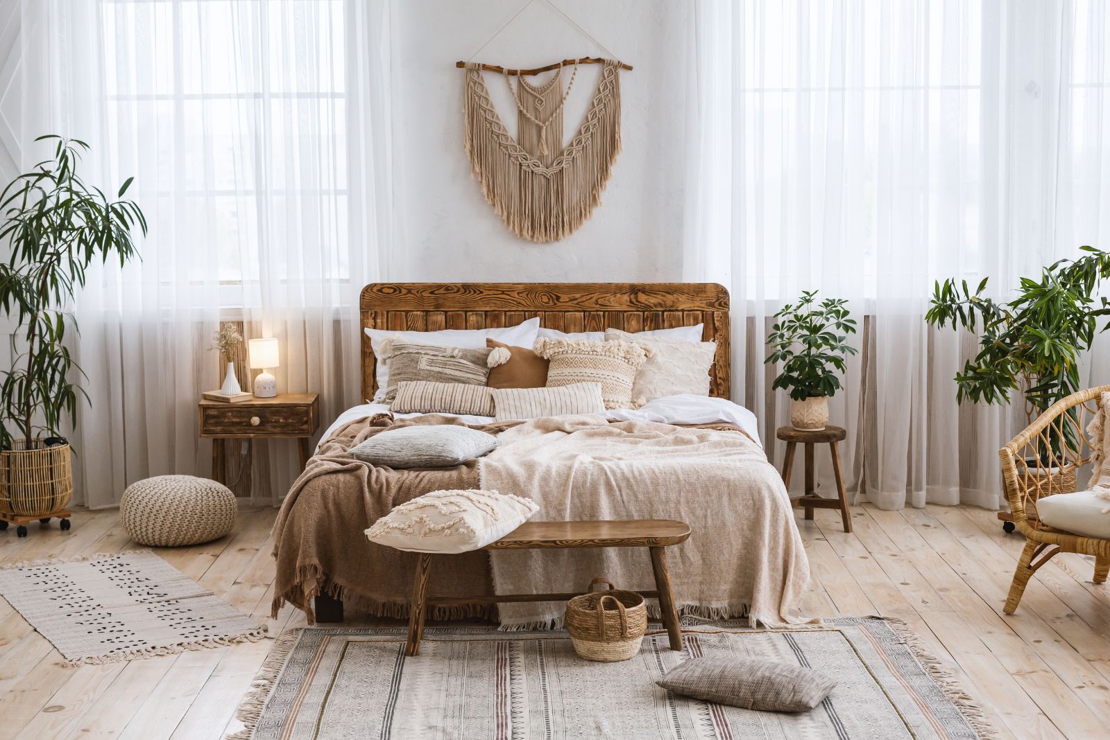 rustic bedroom with a touch of boho, rustic bed, boho details around the room, airy curtains and lots of green plants