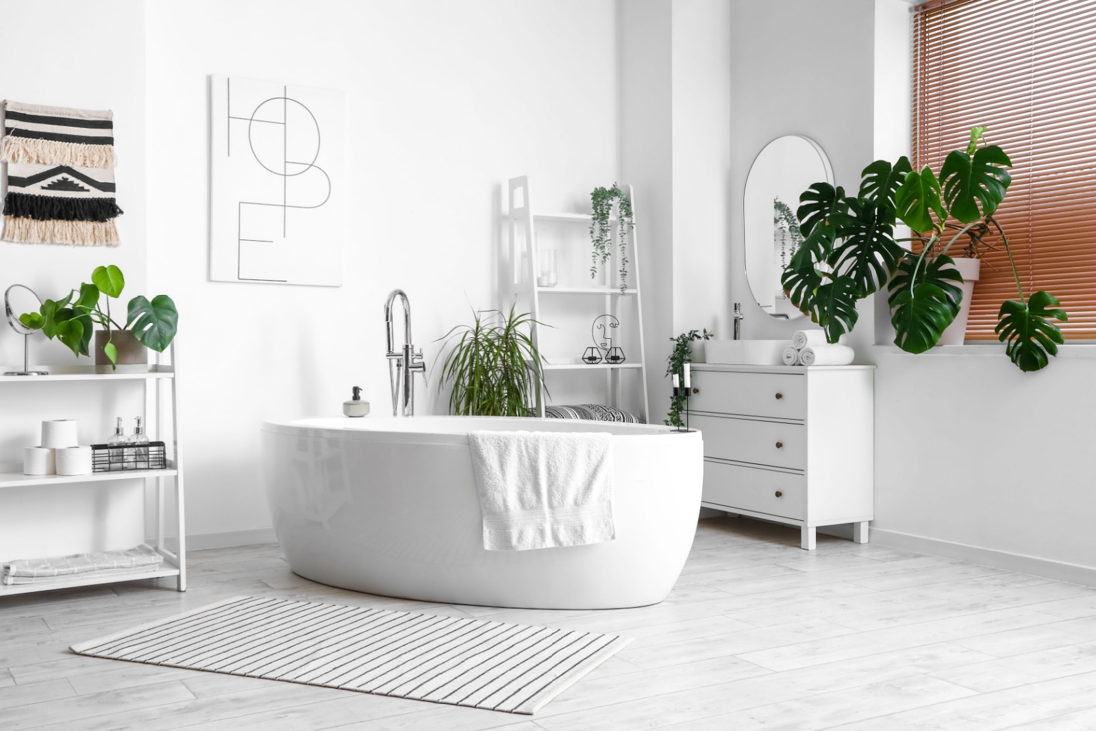 bathroom with a white wall, white bathtub in the middle, white cabinet and white shelves, green plants