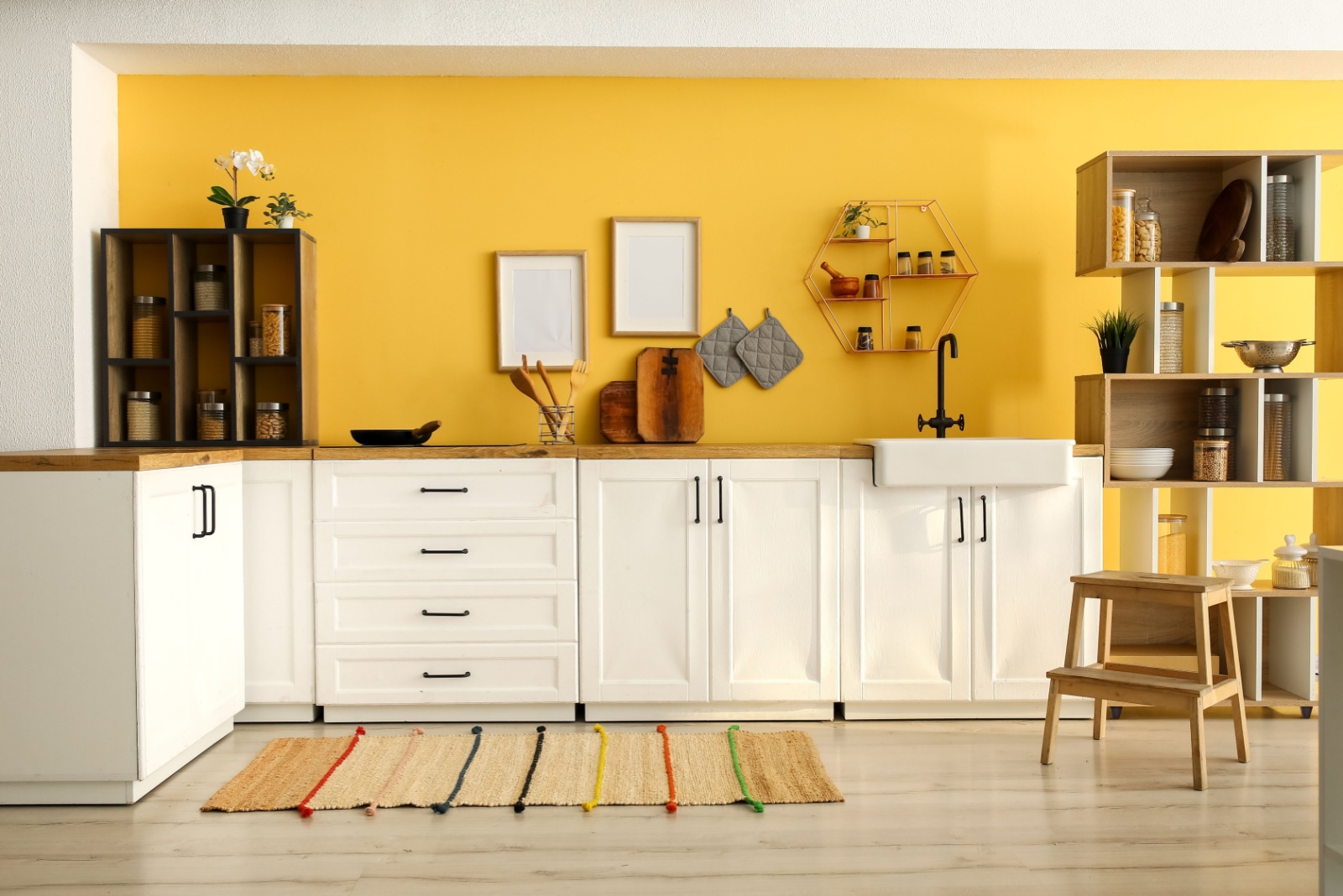 kitchen with a yellow wall, l-shaped countertop with white cabinets