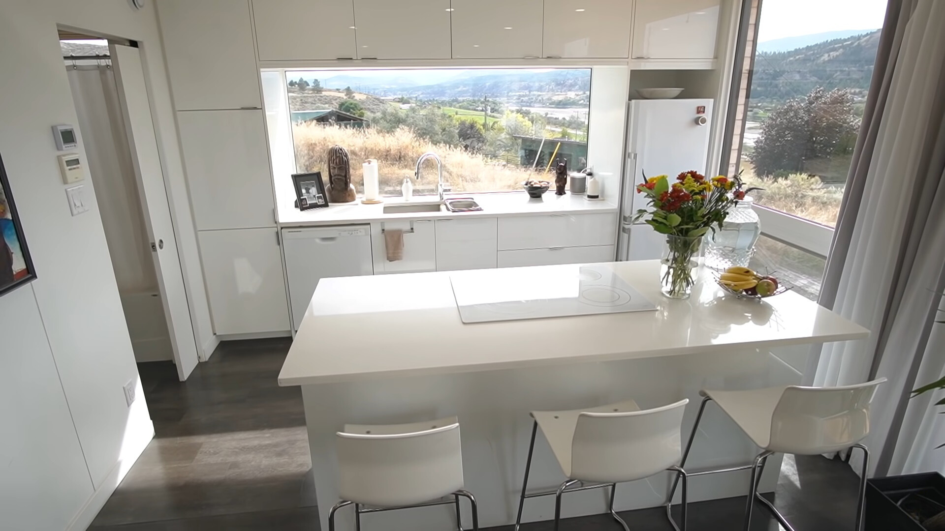 kitchen with white countertops, white cabinets, white bar stools, big windows