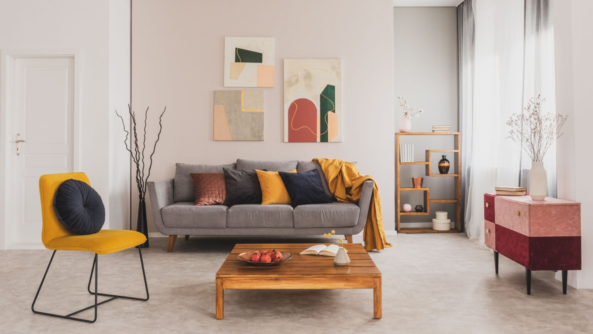 living room with a gray couch, colorful pillows, wooden table and art pieces on the wall