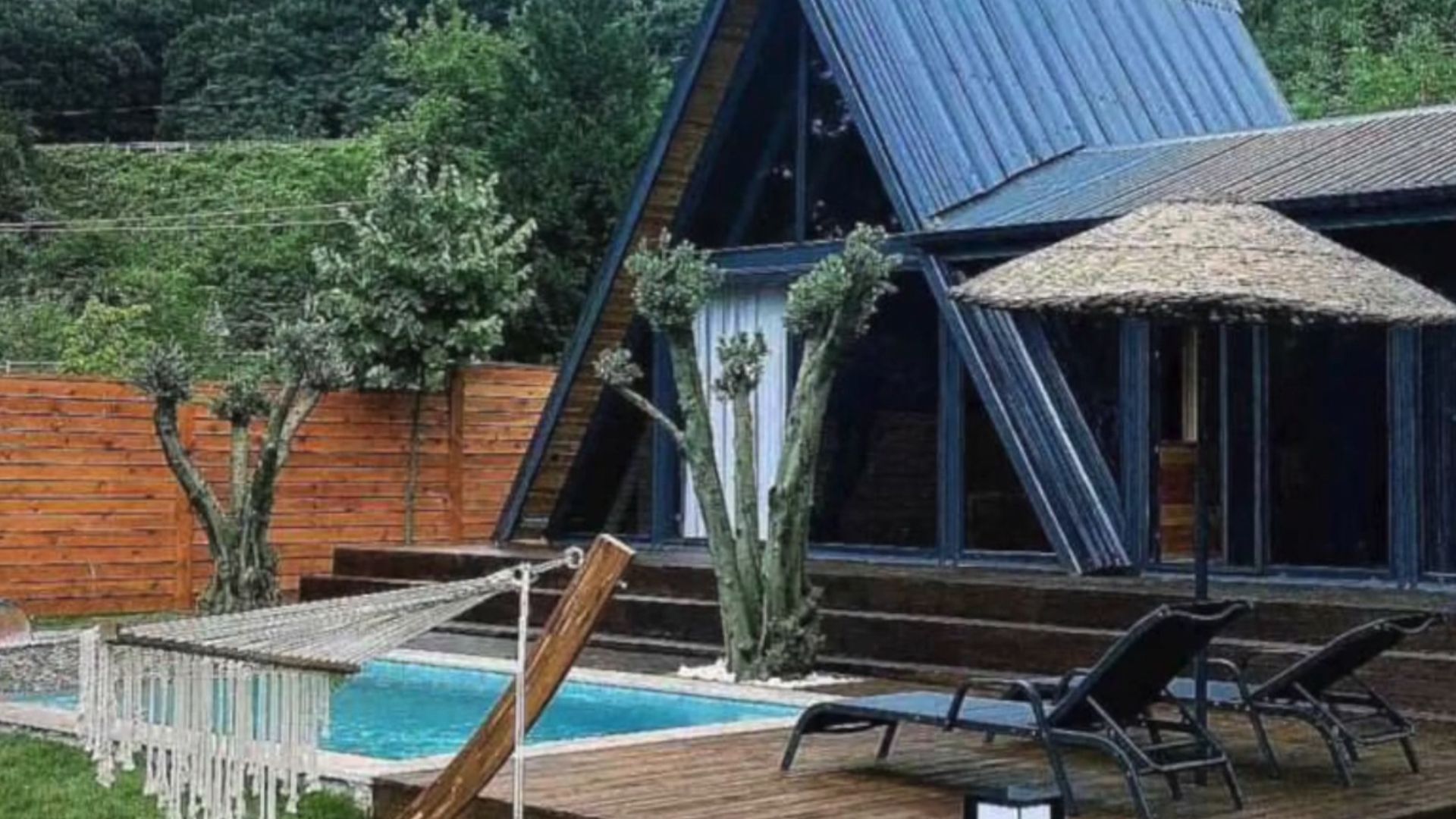 exterior of a tiny house with a-frame roof and a small pool