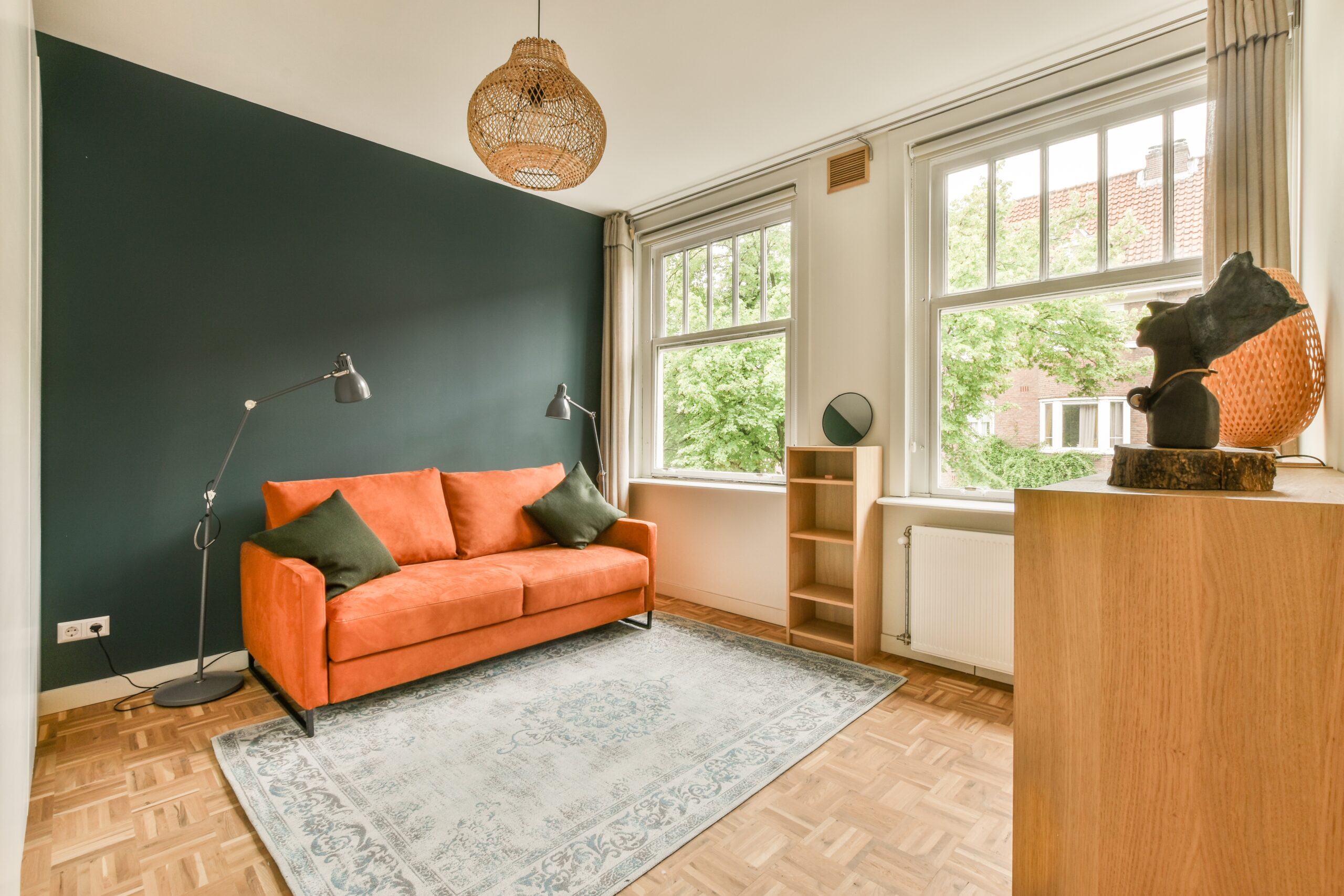 Green accent wall with an orange couch