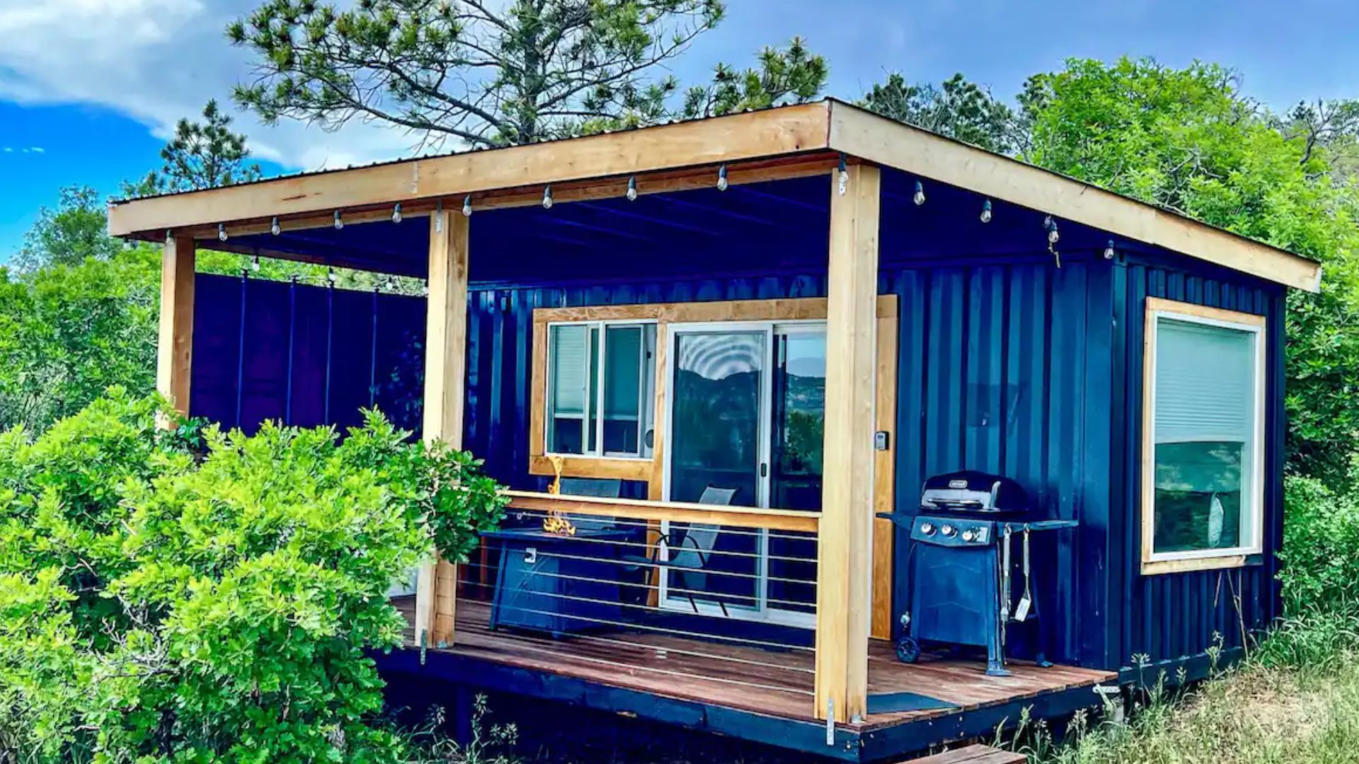 exterior of a black container home with exposed wooden beams and a small porch